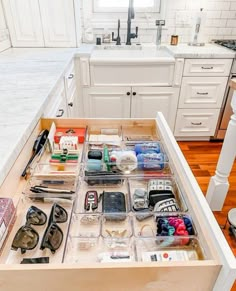 an open drawer in a kitchen filled with personal items