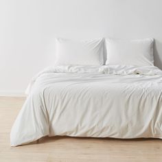 an unmade bed with white sheets and pillows