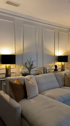 a living room filled with white couches and lamps