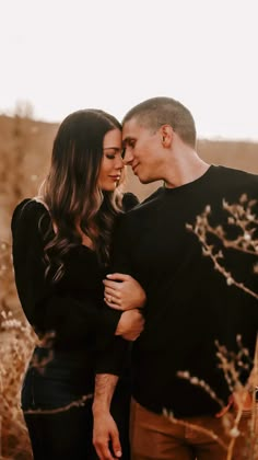 an engaged couple cuddles in the tall grass