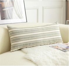 a white couch with a pillow on top of it and a magazine next to it