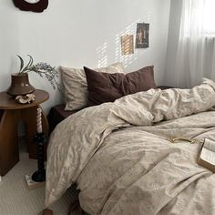 a bed sitting in a bedroom next to a table with a book on it and a clock