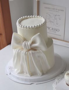 there is a wedding cake with a bow on the top, and two cupcakes next to it