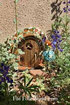 there is a small wooden door in the ground next to some flowers and plants,