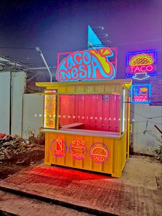 a brightly lit ice cream stand sitting on top of a wooden platform in front of neon signs