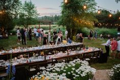 a group of people standing around a long table covered in plates and glasses with candles on it