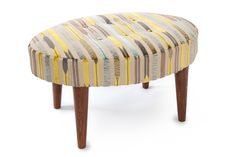 an upholstered foot stool with wooden legs and striped fabric on the top, against a white background