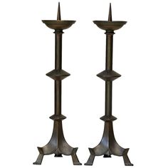 two metal candlesticks sitting next to each other on top of a white background