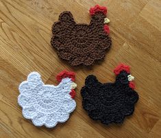 three crocheted chickens sitting on top of a wooden floor