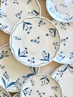 many blue and white plates are stacked on top of each other, with leaves painted on them