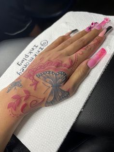 a woman's hand with pink and black tattoos on her left arm, sitting in a car seat