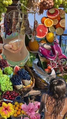 a woman standing in front of a display of fruits and vegetables on a table next to the ocean