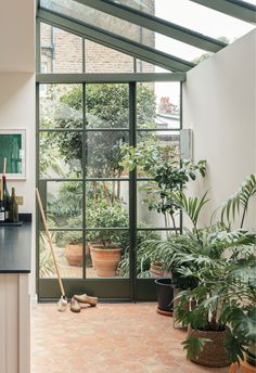 a kitchen with an orange tiled floor and green plants in the window sill next to it