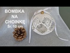 an ornament next to a pine cone on top of a gray table cloth