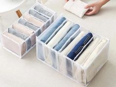 two clear storage bins filled with pairs of folded jeans on top of a table