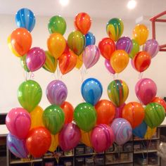 a bunch of balloons that are hanging from the ceiling in front of a bookcase