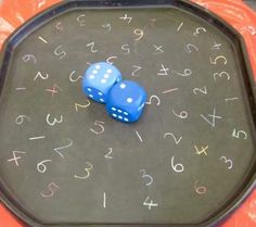 two blue dices sitting on top of a black tray with numbers drawn on it