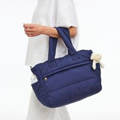 a woman carrying a blue bag with a stuffed animal in it's back pocket