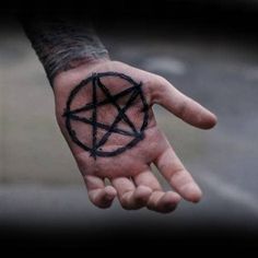 a person's hand with a pentagramil tattoo on it