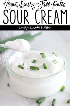 a jar filled with sour cream sitting on top of a white table next to green onions