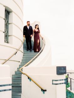 a man and woman walking up some stairs