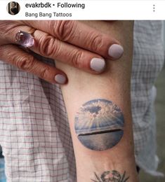 a woman's arm with a tattoo on it that has an image of a beach and palm trees