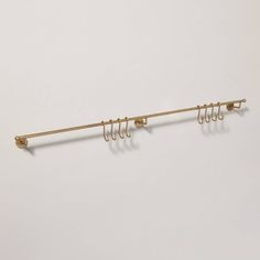 a metal rack with five hooks and four clips on the end, hanging from a white wall