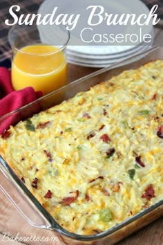 an egg casserole in a pan on a table with orange juice and strawberries