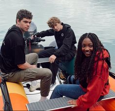 three people sitting on a boat in the water