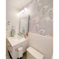 a bathroom with blue and white wallpaper, toilet and sink in the foreground