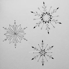 three snowflakes drawn in black ink on white paper, each with different shapes and sizes