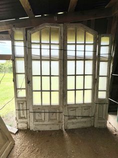 an open window in the corner of a room with dirt on the floor and grass behind it