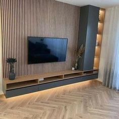 a living room with wood flooring and a large television on the entertainment center wall