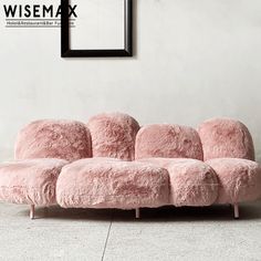 a pink couch sitting on top of a white floor next to a black framed photo