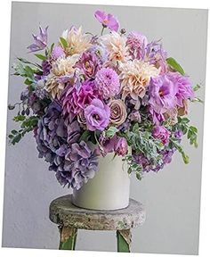 a white vase filled with lots of purple flowers