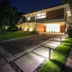 a modern house lit up at night with lights on the front and side of it