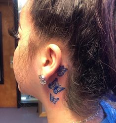 a woman's ear with butterfly tattoos on her left side and behind the ear