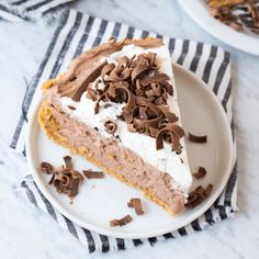 a slice of chocolate ice cream pie on a white plate with a black and white striped napkin