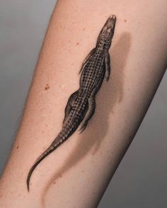 a small lizard tattoo on the right arm and leg, it looks like an alligator