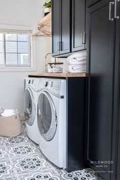 a washer and dryer in a small room with black cupboards on the wall