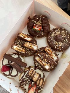 a box filled with lots of different types of donuts and pastries on top of a table