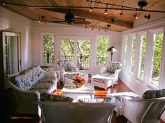 a living room filled with white furniture and lots of windows covered in wood planks