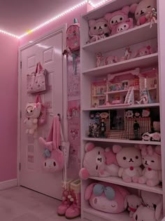 a pink room with teddy bears and stuffed animals on shelves in the corner next to a door