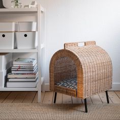 a wicker chair sitting in front of a book shelf next to a white wall