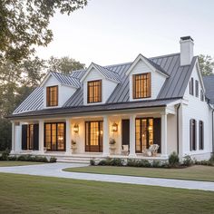 a white house with black shutters and two story windows on the front porch, surrounded by grass