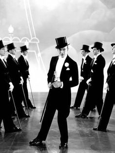 a group of men in suits and top hats standing next to each other with canes