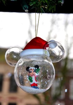 a mickey mouse ornament hanging from a christmas tree in front of a window