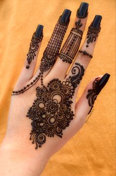 a woman's hand with henna tattoos and black nail polishes on it