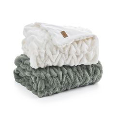 three blankets stacked on top of each other, one green and the other white in color