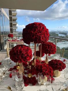 the table is set with red roses and gold vases